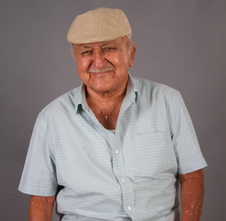 Señor mayor sonriendo con gorra y camisa celeste